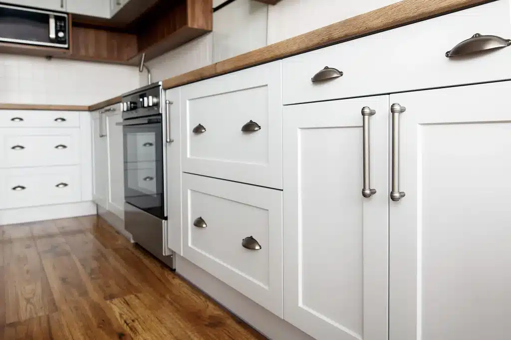 White kitchen cabinets with hardware installed in a newly prepared kitchen.